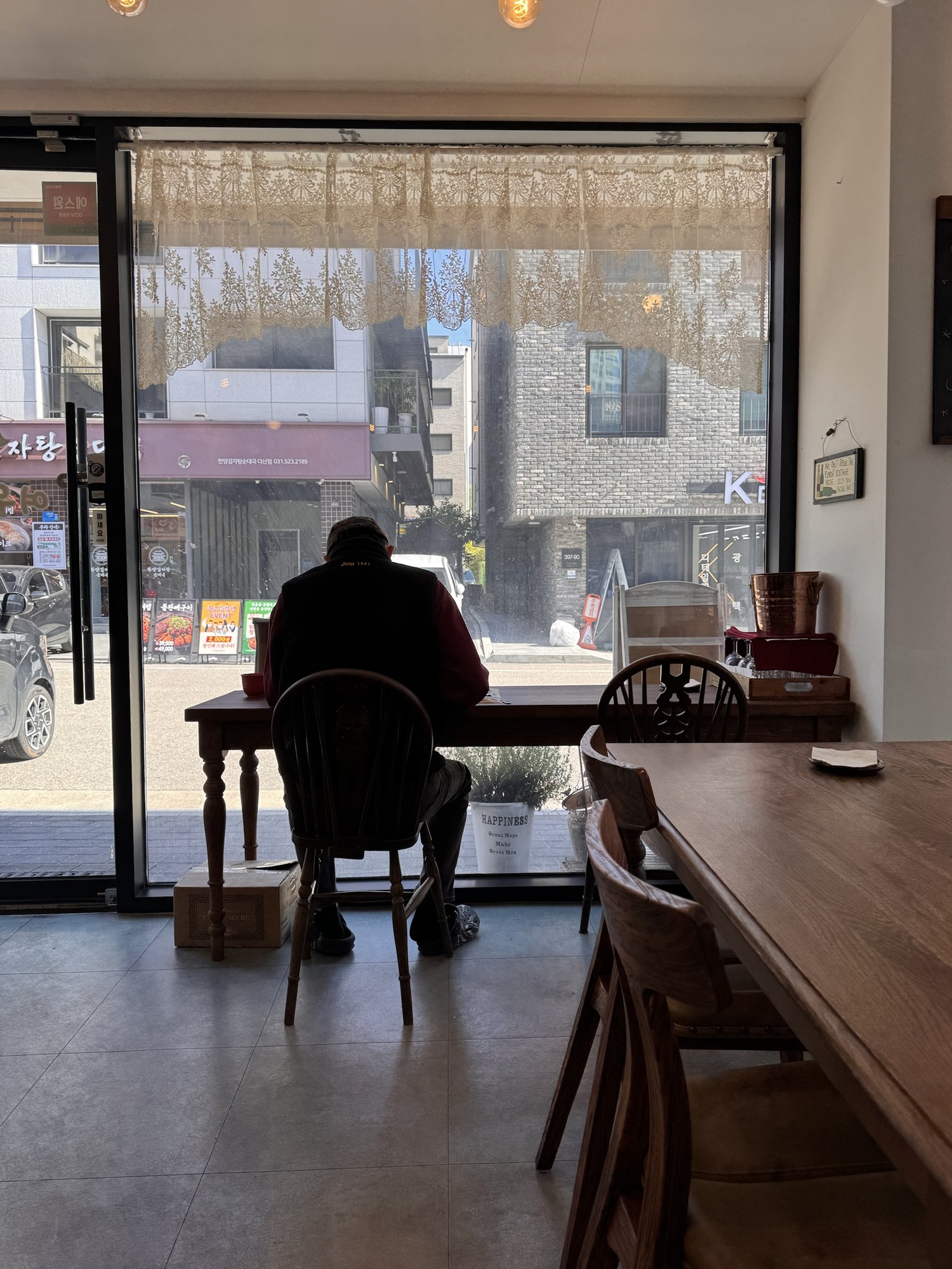 볕 드는 창가 자리에 혼자 앉은 사람의 뒷모습